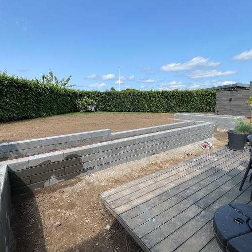 Opbygning af hævet bed i grå blokke ved terrasse og haveareal.