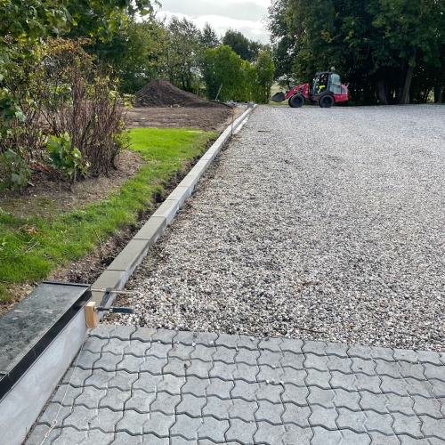 Lang grusindkørsel med ny kantafgrænsning set fra belagt overgang.